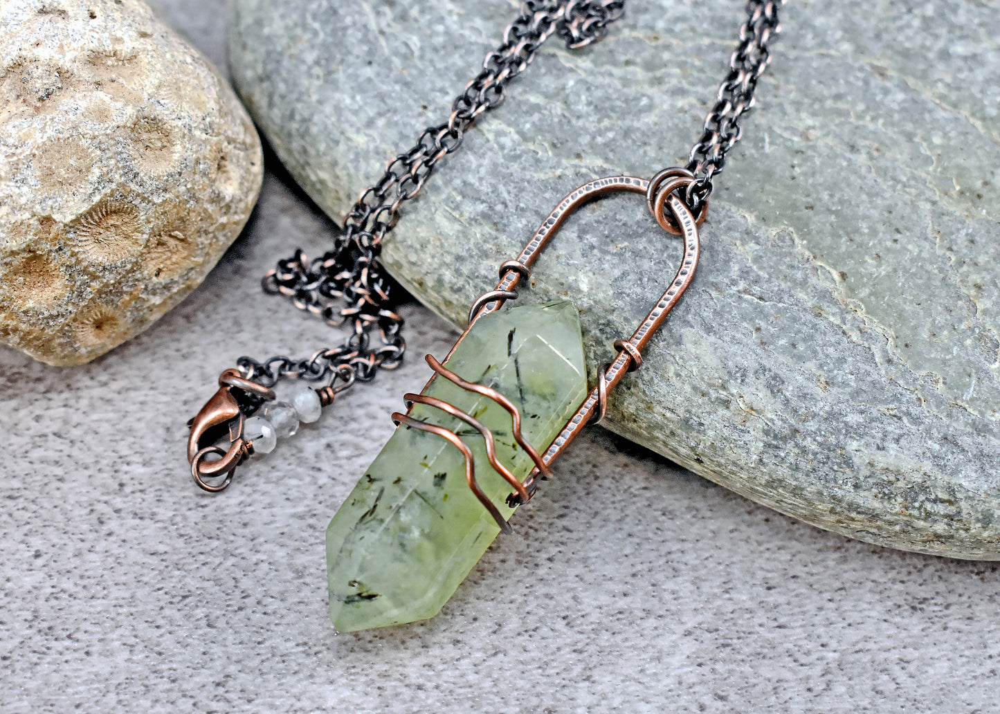 Necklace with a green stone pendant on a stone surface